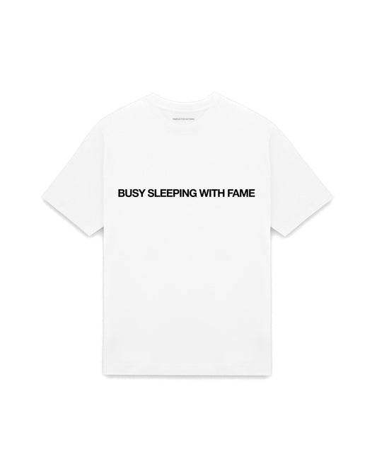 White oversized t-shirt with BUSY SLEEPING WITH FAME printed in Helvetica across the chest, AS Colour Heavy Tee 5080.