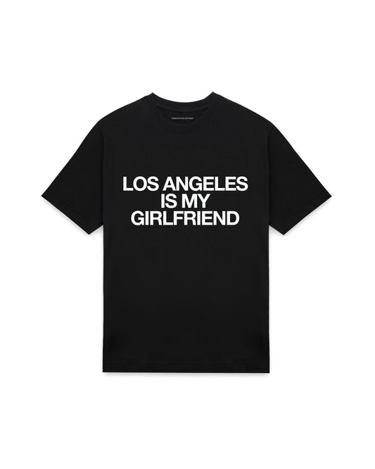 Black oversized t-shirt with LOS ANGELES IS MY GIRLFRIEND printed in Helvetica across the chest, AS Colour Heavy Tee 5080.