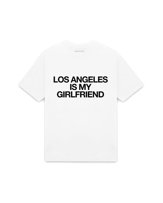 White oversized t-shirt with LOS ANGELES IS MY GIRLFRIEND printed in Helvetica across the chest, AS Colour Heavy Tee 5080.